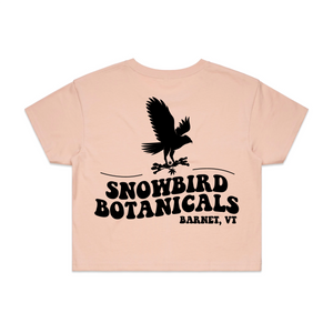 Pink Crop Top with a big design on the back of a snowbird and the text "Snowbird Botanicals Barnet, VT" underneath.