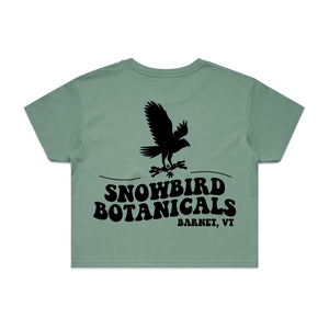 Sage Crop Top with a big design on the back of a snowbird and the text "Snowbird Botanicals Barnet, VT" underneath.